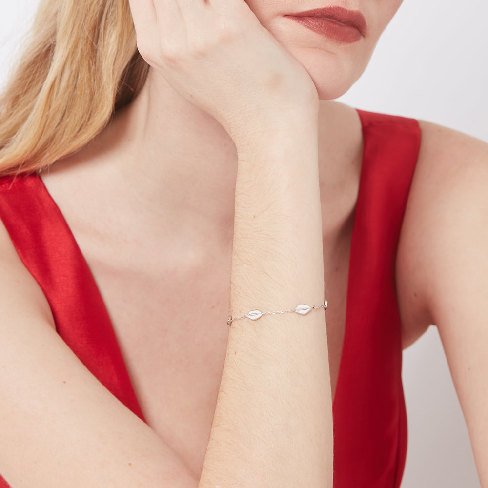 Sterling silver lip charm bracelet worn by a model in a red dress.