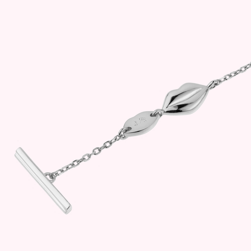 Close up image of a sterling silver lip charm bracelet showing the t-bar fastening and engraved L.G monogram.