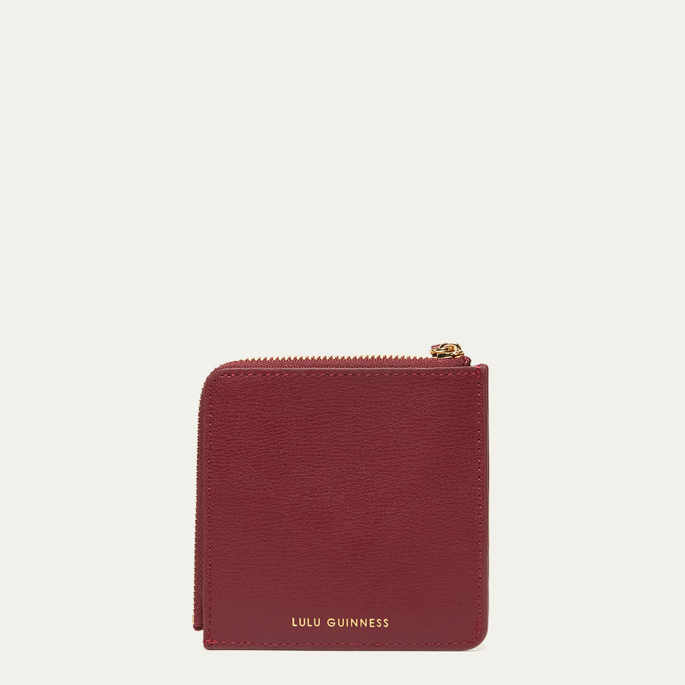 Red wallet with gold zipper and 'Lulu Guinness' branding on a white background