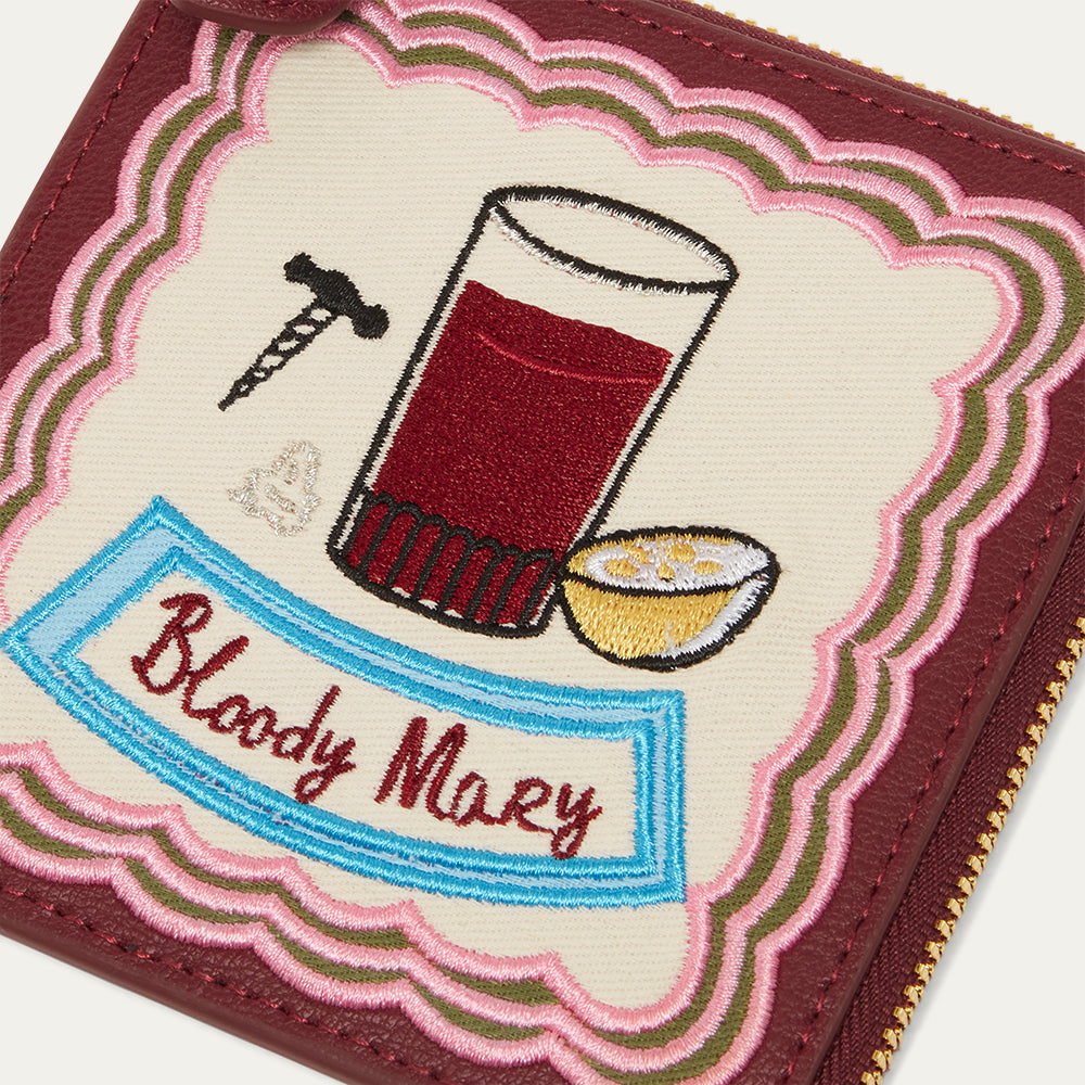 Embroidered design of a Bloody Mary  cocktail on a wallet with text and graphics.