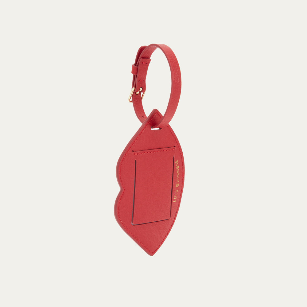 Red leather luggage tag on a light beige background