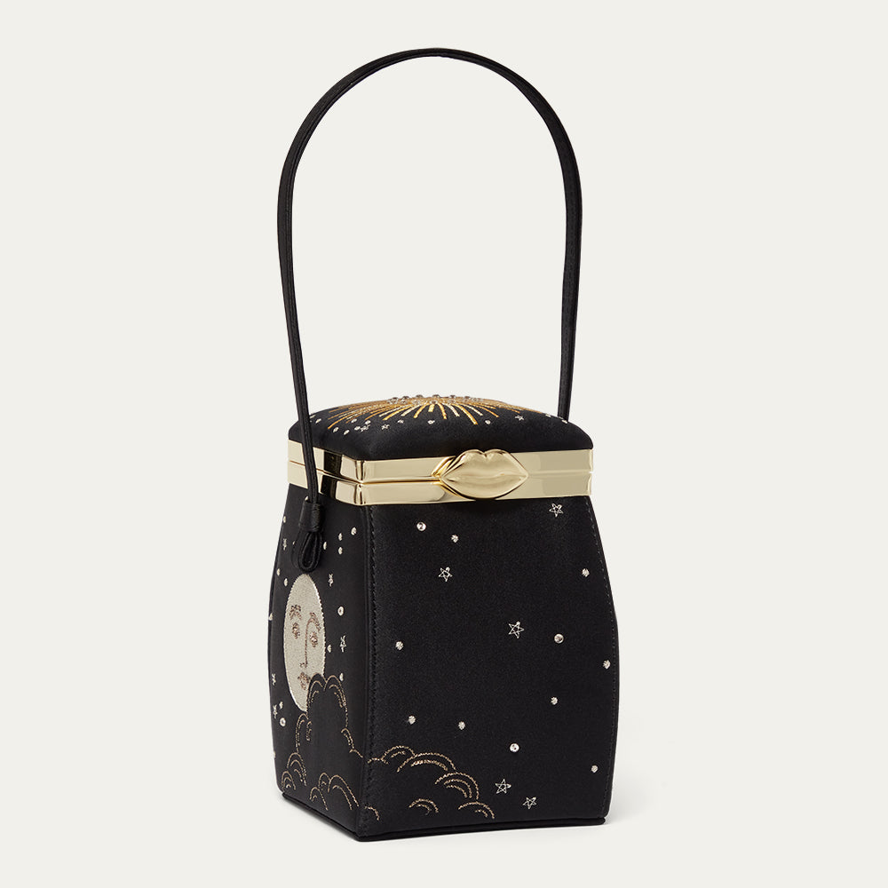 Black satin handbag with gold accents and celestial designs on a light gray background