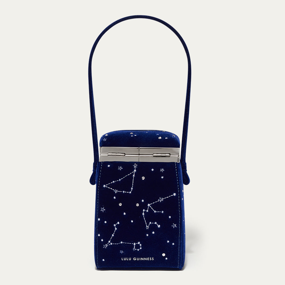 Navy blue velvet handbag with star constellation design and 'Lulu Guinness' branding on a light gray background