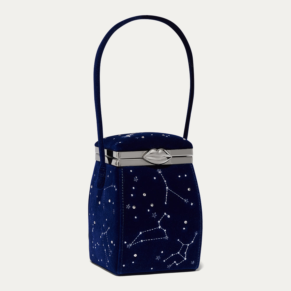 Navy blue velvet handbag with star constellation design on a light gray background