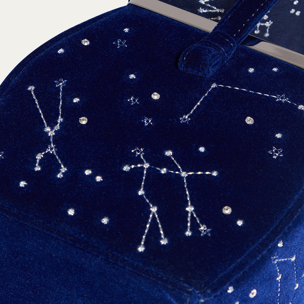 Navy velvet bag with embroidered star constellations on a white background