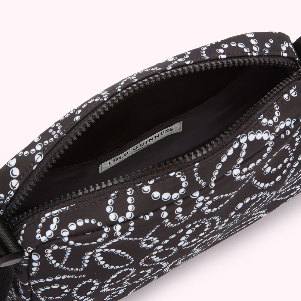 Black Lulu Guinness crossbody bag with white pearl pattern, open to show black interior and brand label.