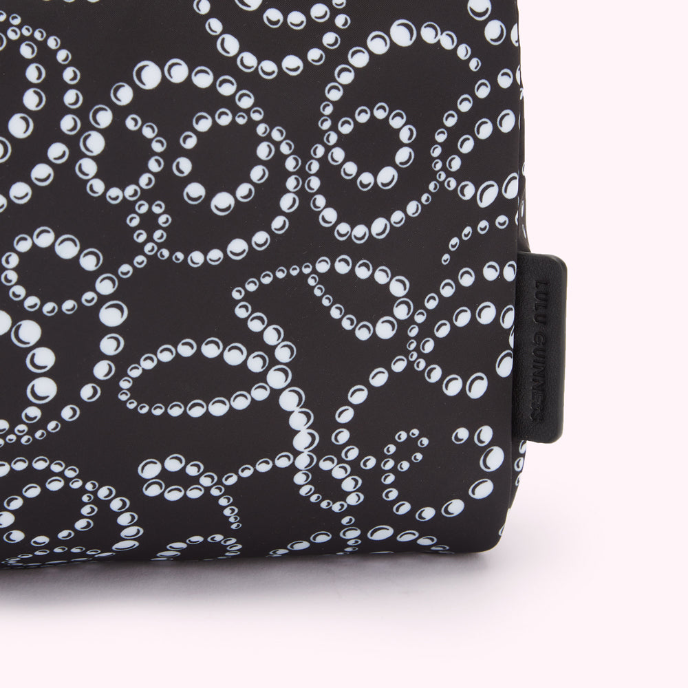 Close-up of a Lulu Guinness black cosmetic bag with a white pearl pattern.