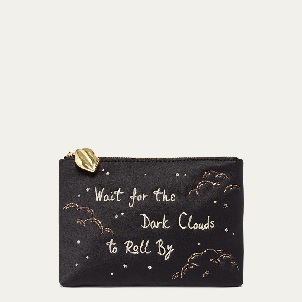 Black satin pouch with gold text and cloud designs on a beige background