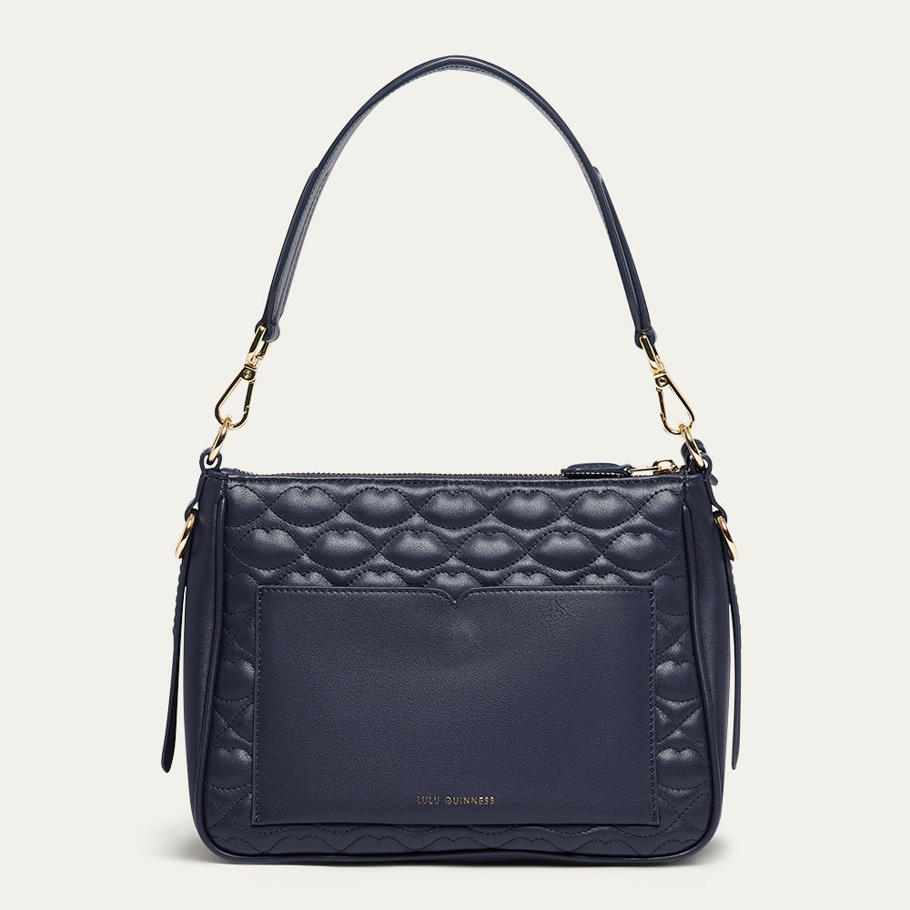 Navy blue leather quilted handbag with gold accents on a light gray background