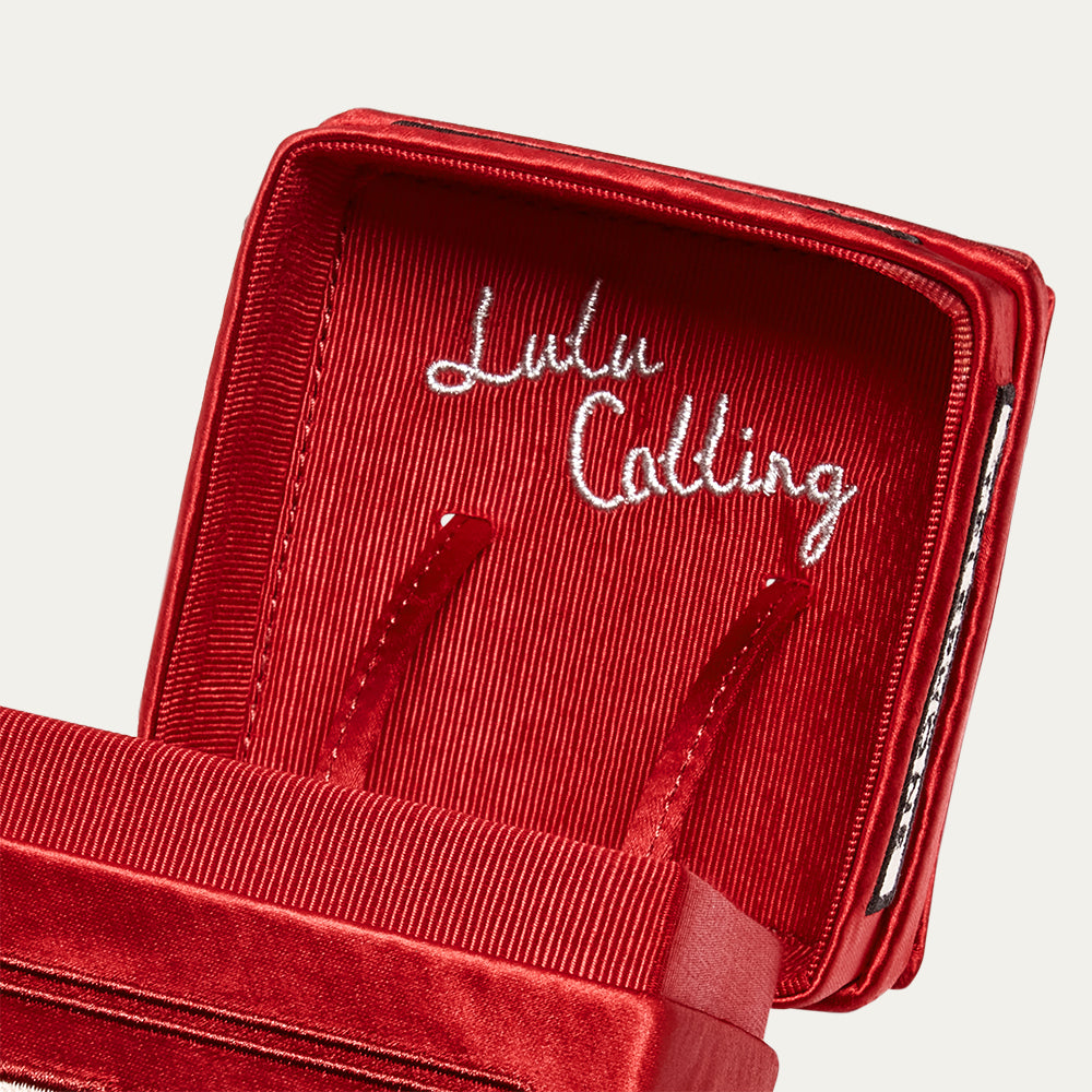 Close up image of the inside lid of a phone box shaped bag reading 'Lulu Calling' in embroidery