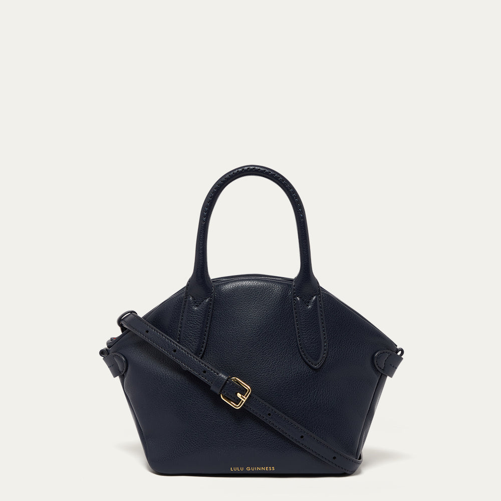 Navy leather handbag with gold buckle on a light gray background