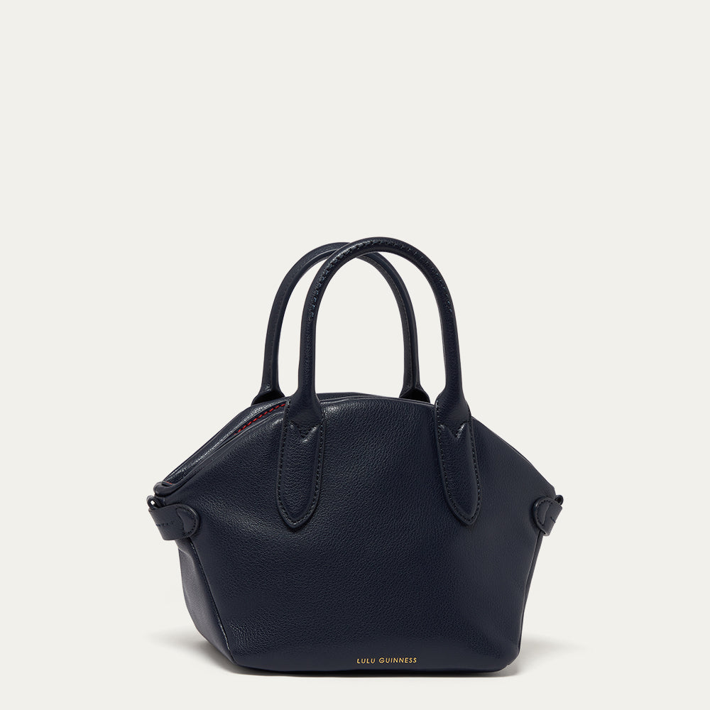 Navy leather handbag with handles on a light beige background