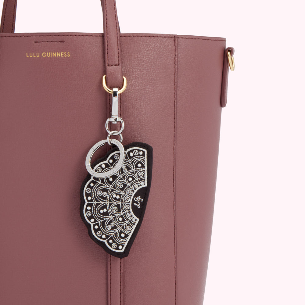 Close-up of a mauve Lulu Guinness tote bag with a fan-shaped keychain.