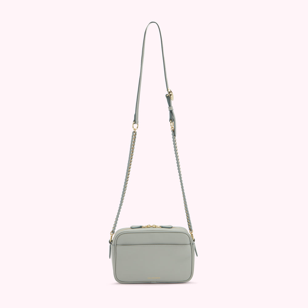 A light sage green crossbody bag with a gold chain strap and zipper closure.
