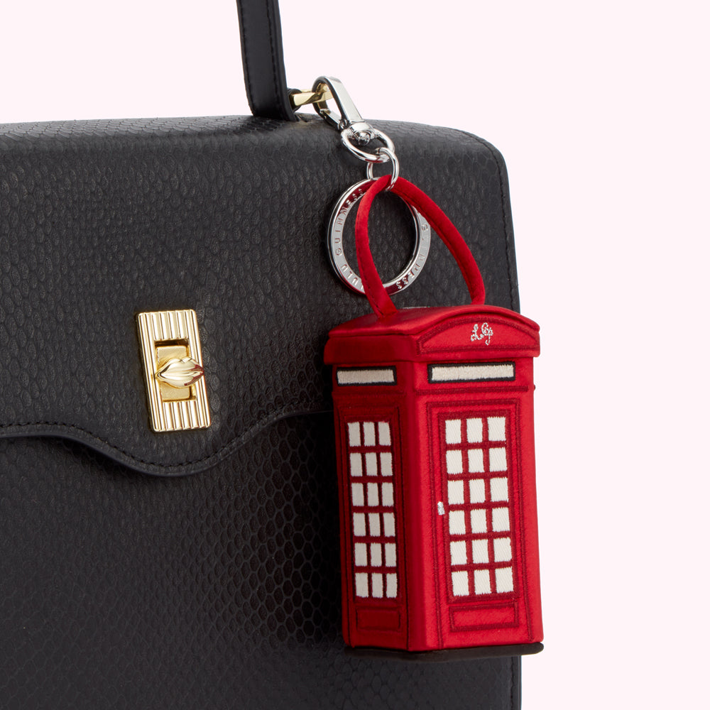 Red telephone booth-shaped keychain attached to a black handbag.