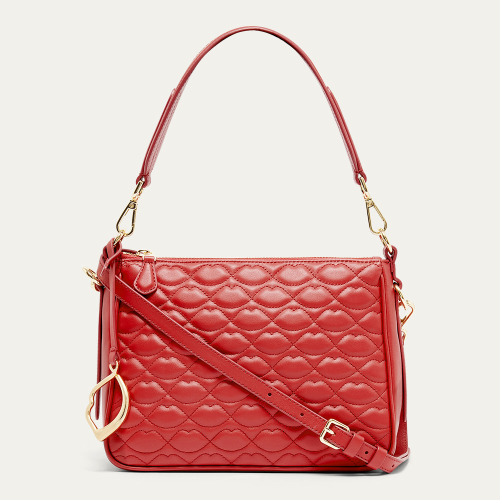 Red quilted handbag with gold accents on a light beige background