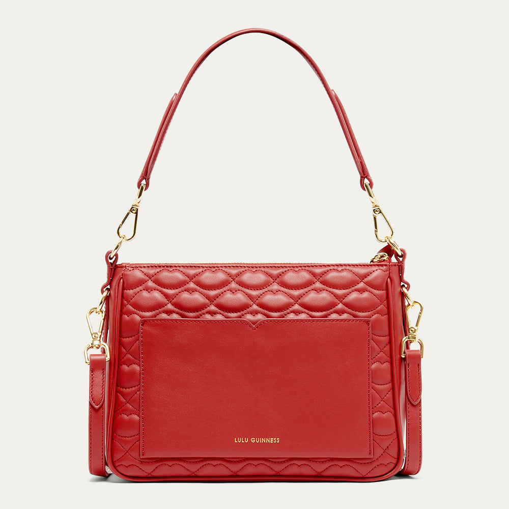 Red quilted handbag with gold accents on a light gray background