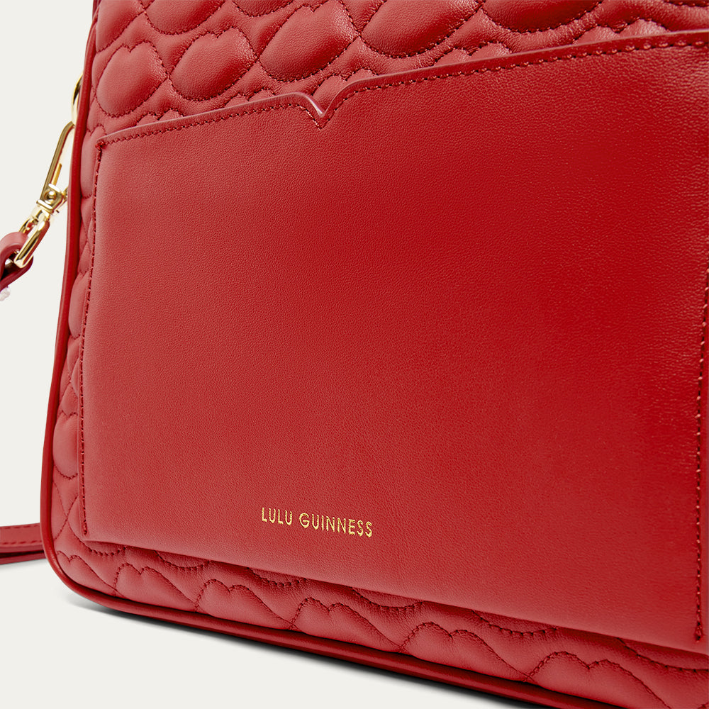 Red handbag with quilted design and gold clasp on a light gray background