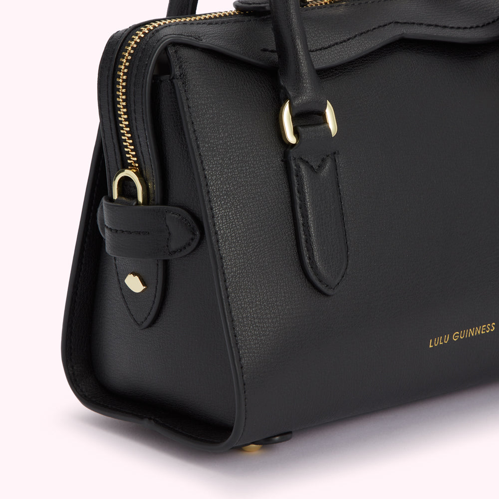 Close-up of a black Lulu Guinness leather handbag with gold hardware.