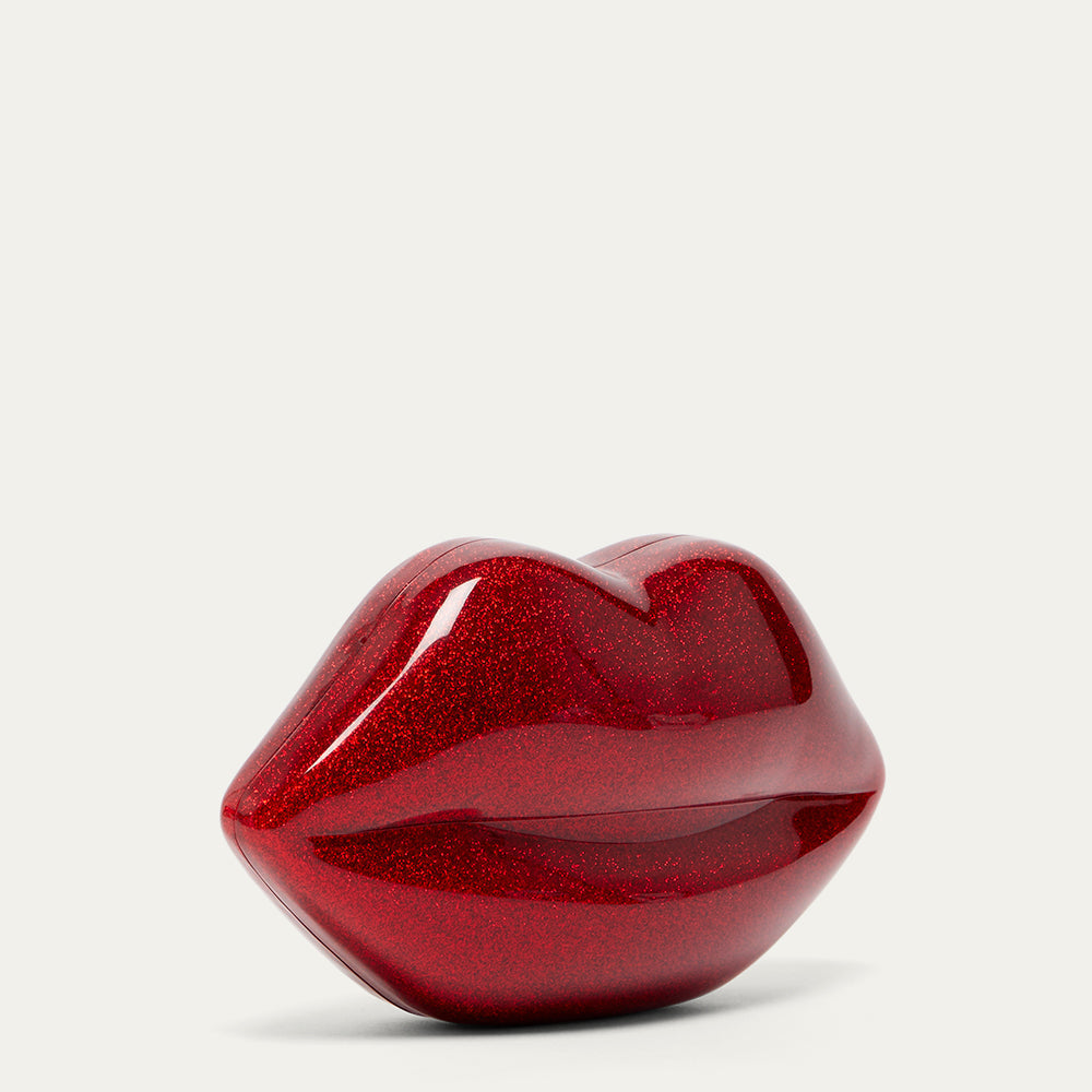 Red glittery lips-shaped clutch bag on a light gray background