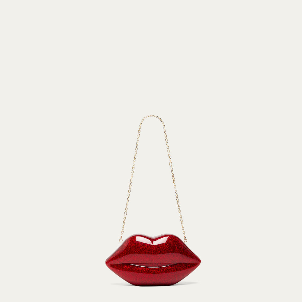 Red lip-shaped handbag with a gold chain on a light beige background