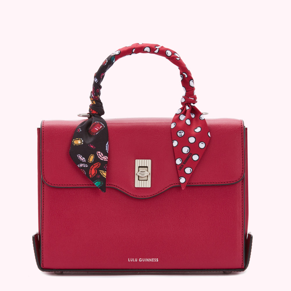 Red Lulu Guinness satchel bag with a patterned scarf handle.