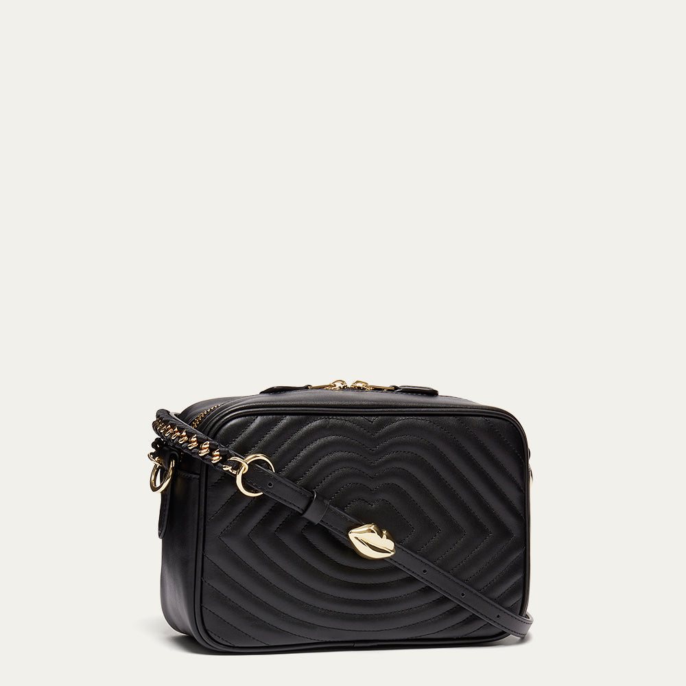 Black quilted handbag with gold accents on a light gray background