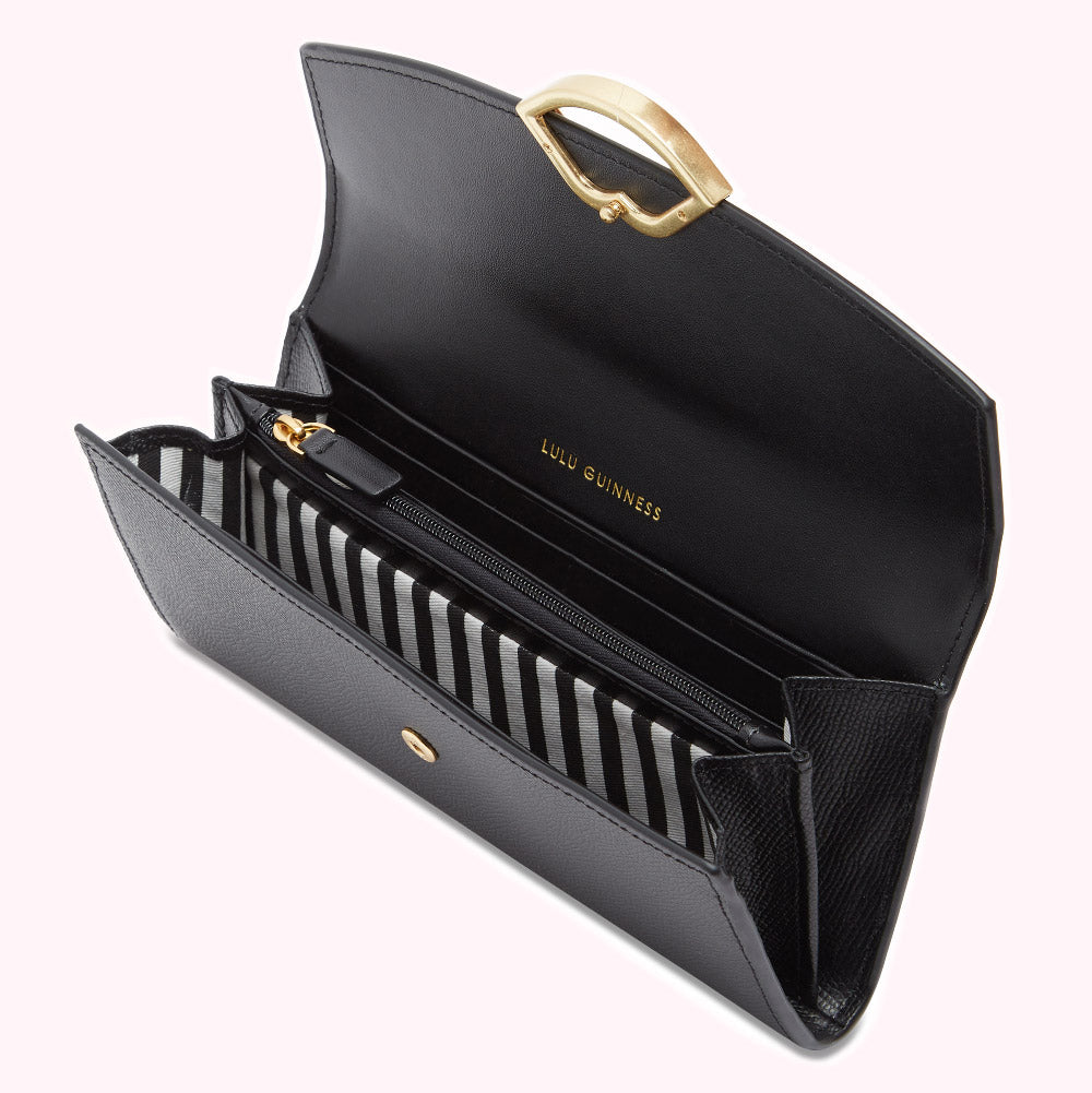 Open black Lulu Guinness wallet with gold heart-shaped clasp and black and white striped interior.
