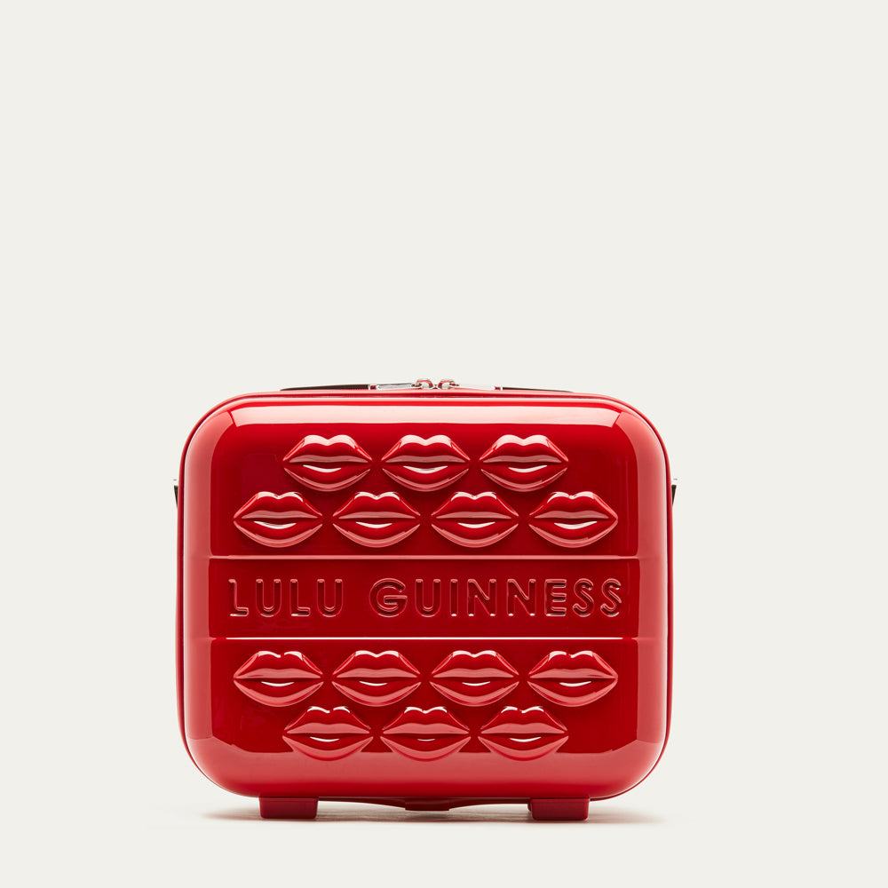 Red vanity case with lips pattern and 'Lulu Guinness' branding on a light gray background