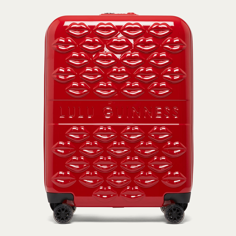 Red suitcase with lip pattern and 'Lulu Guinness' branding on a white background