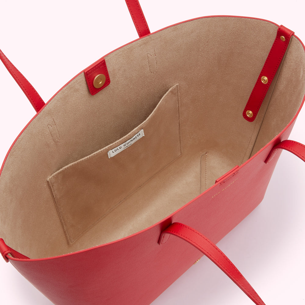 Red Lulu Guinness tote bag viewed from above, showcasing the beige interior and small interior pocket.
