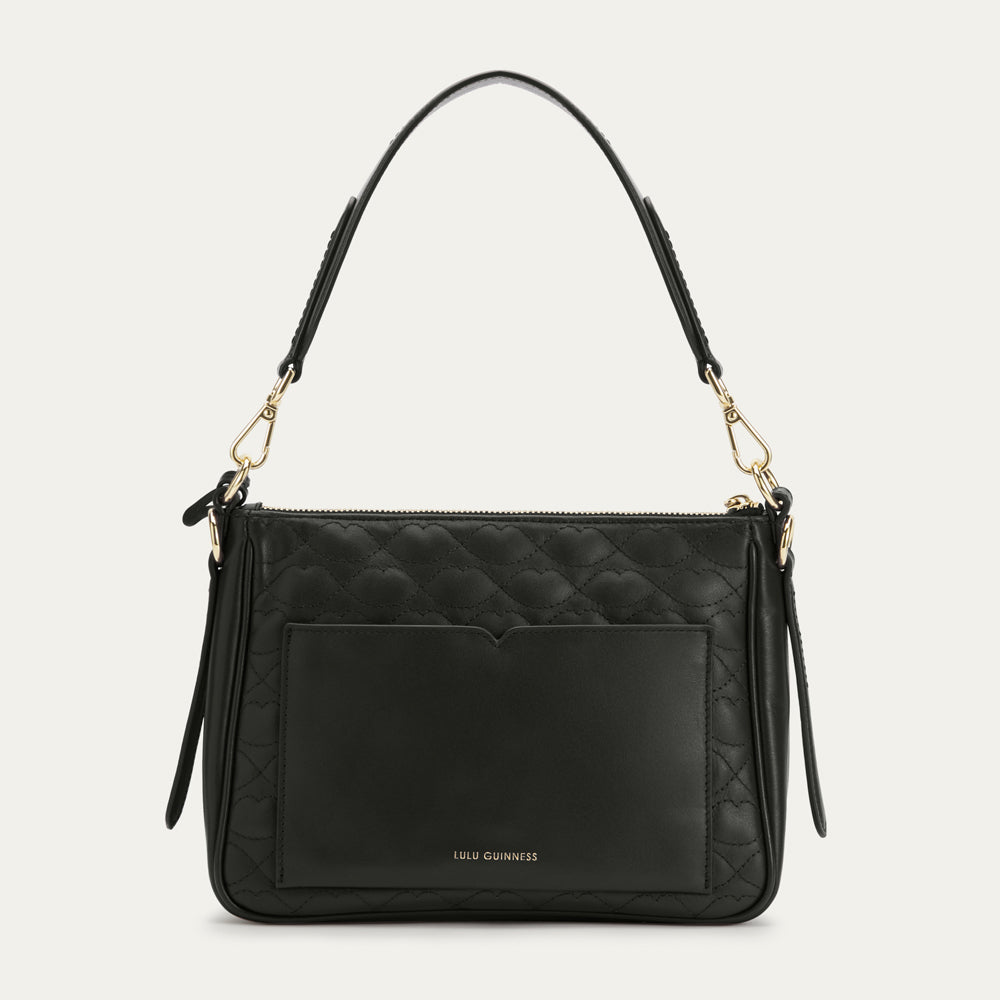 Black quilted handbag with gold accents on a light gray background