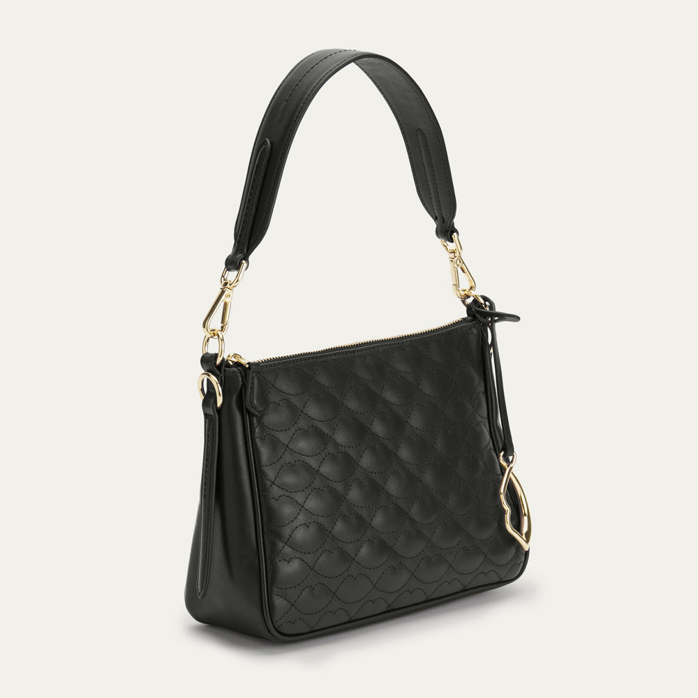 Black quilted handbag with gold accents on a light gray background