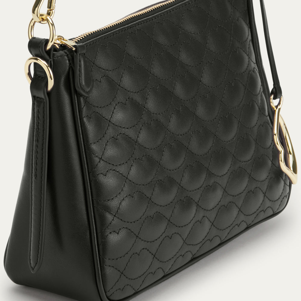 Black quilted handbag with gold accents on a light gray background