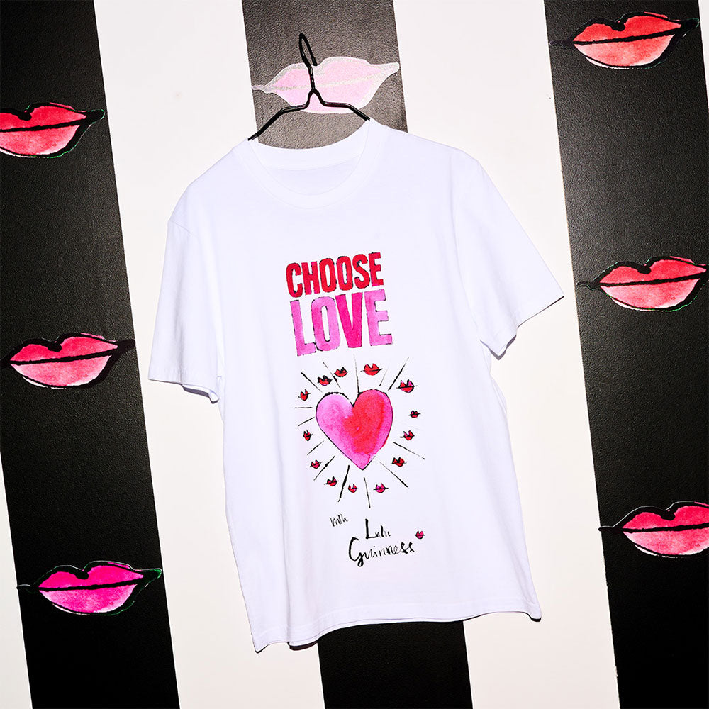 White Choose Love with Lulu Guinness collaboration t-shirt hanging against a striped and lip print background.