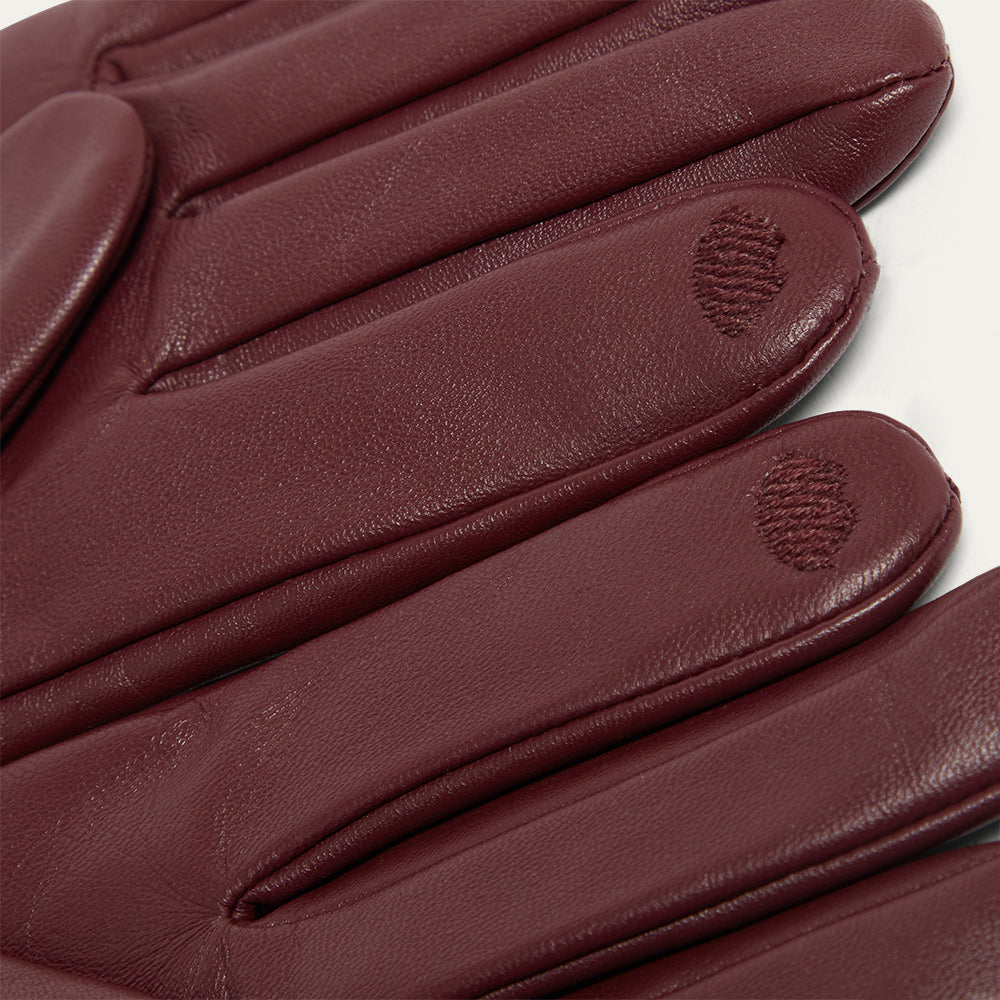 Close-up of burbundy leather gloves with a visible brand logo on a white background