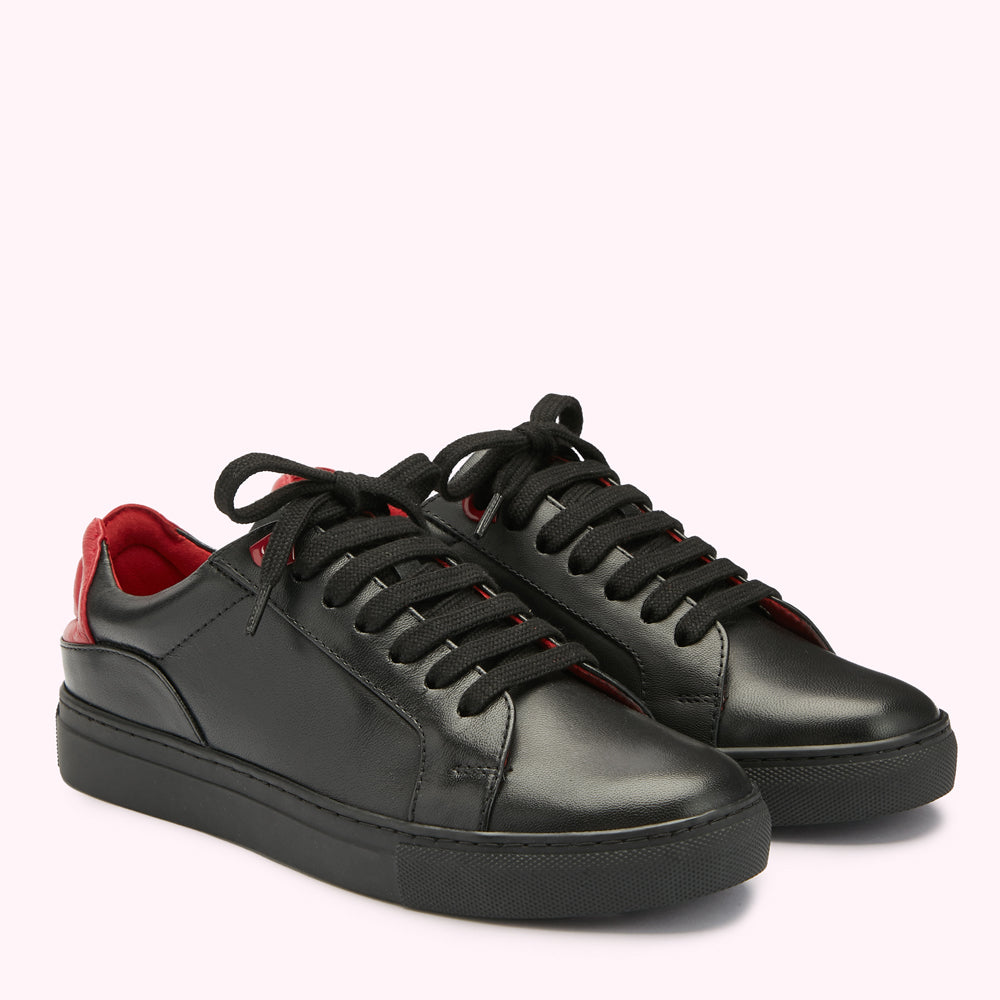 Pair of black leather sneakers with red accents on a white background.