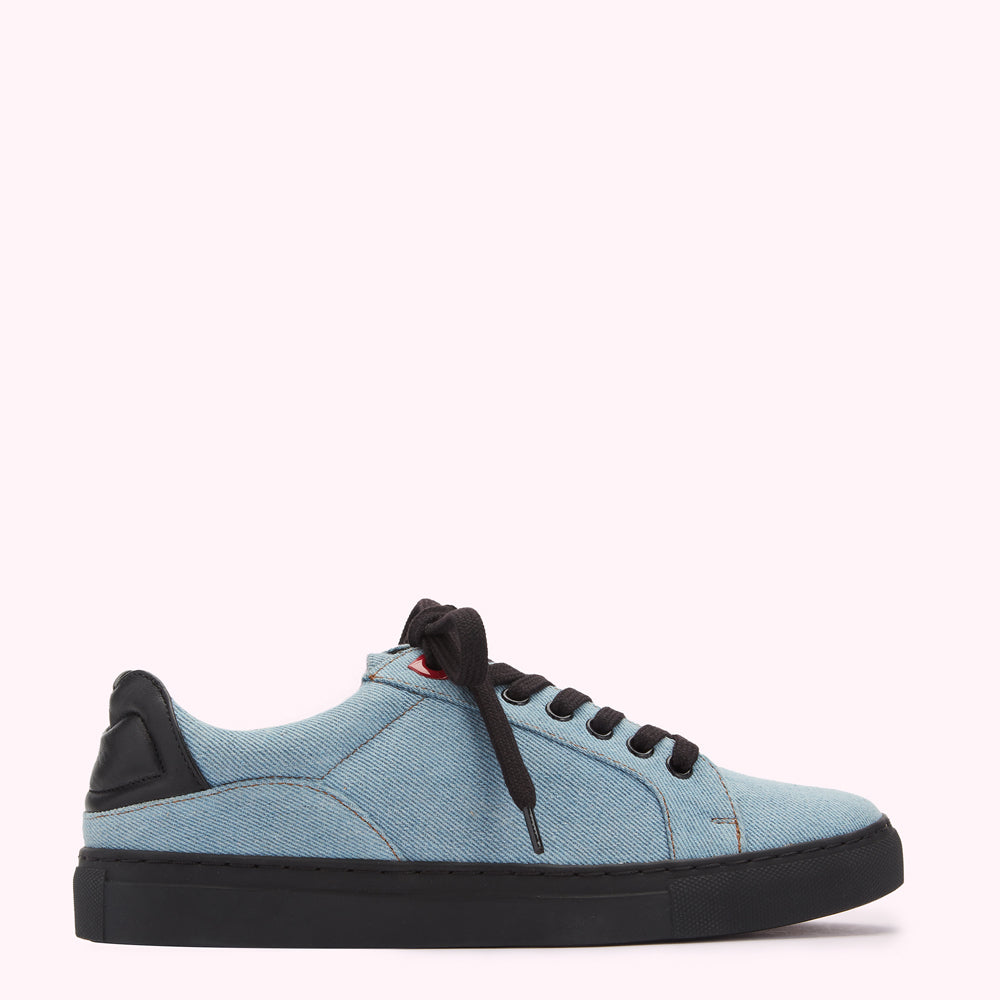 Light blue denim low-top sneaker with black laces and sole against a white background.
