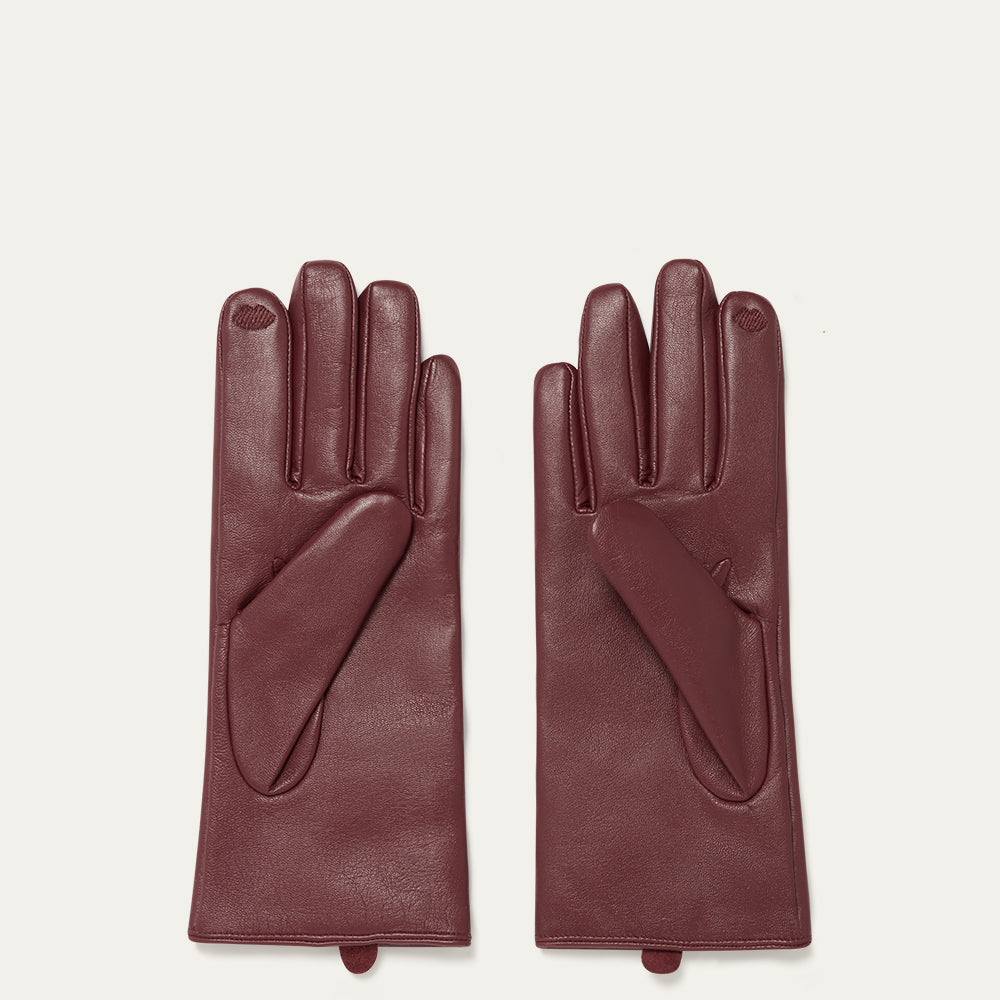 Pair of burgundy leather gloves on a light beige background