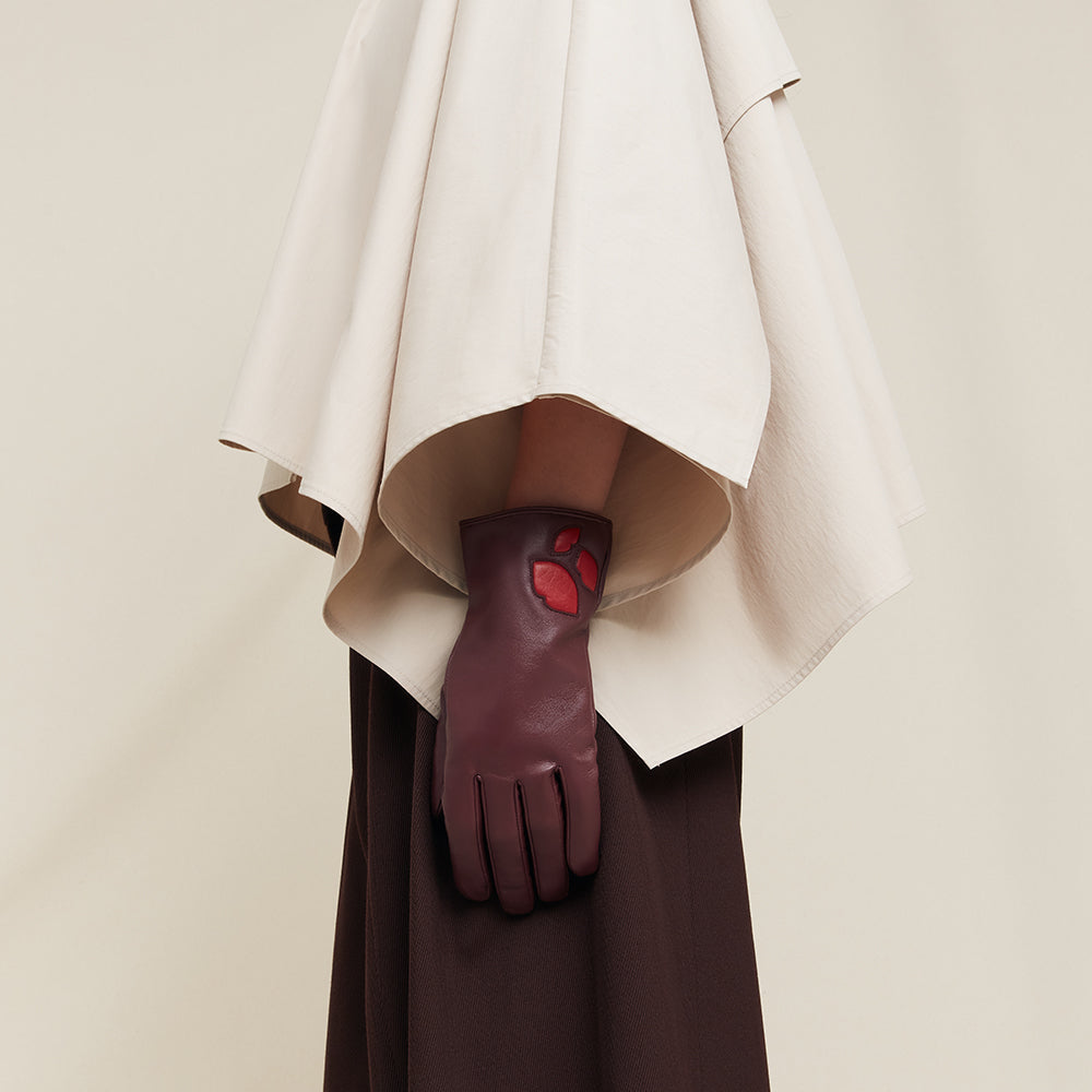 Burgundy leather glove with red accents on a neutral background