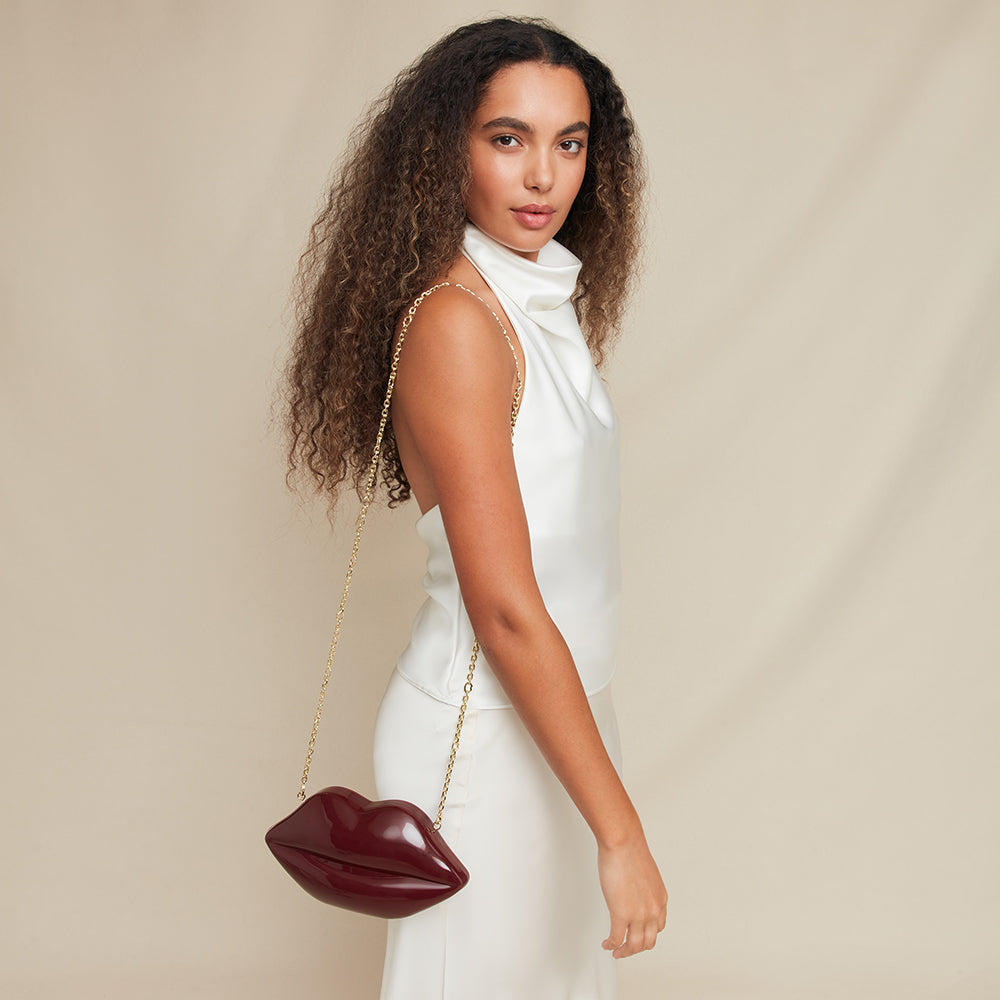 Woman holding a lip-shaped handbag against a beige background