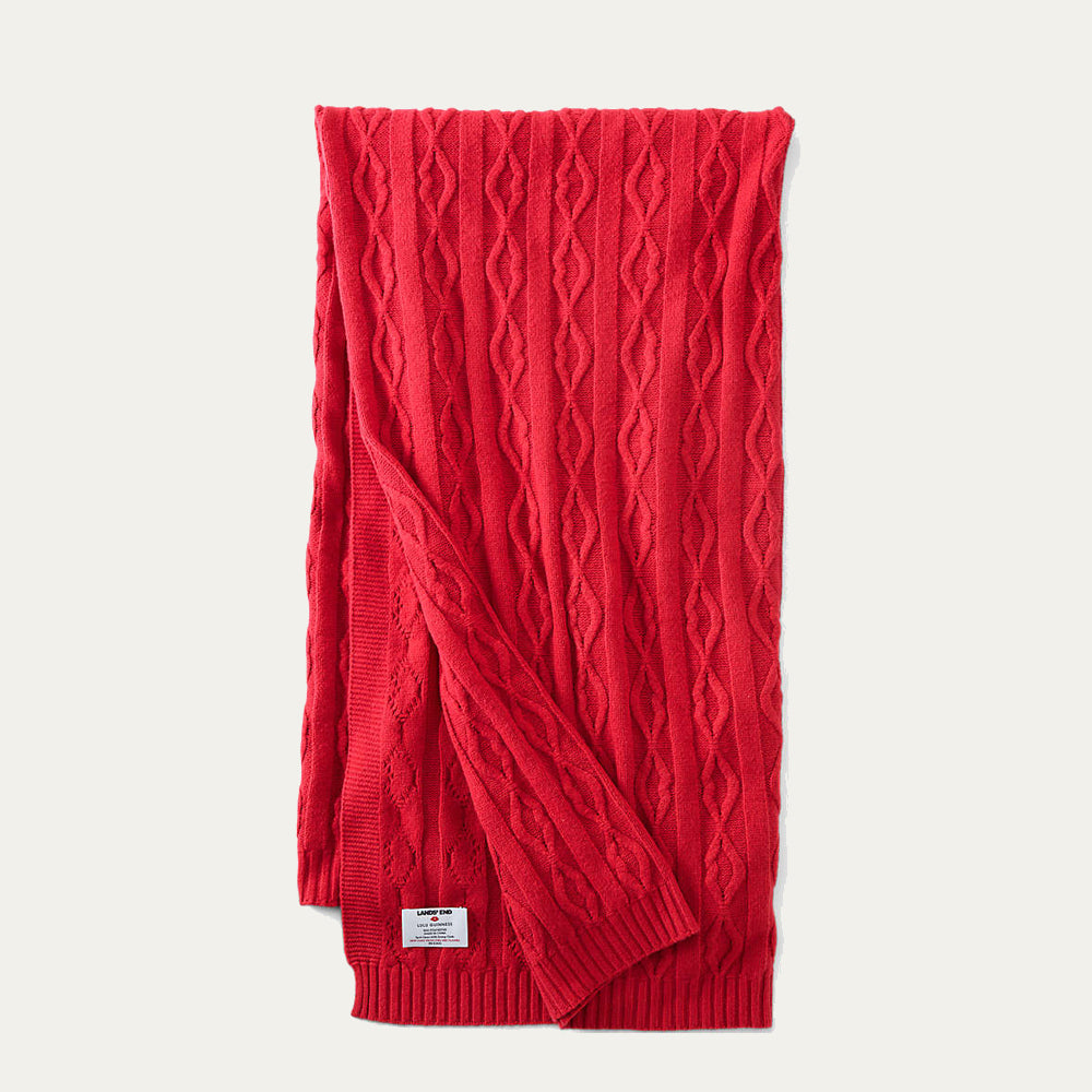A red lip cable knit throw folded on a beige background