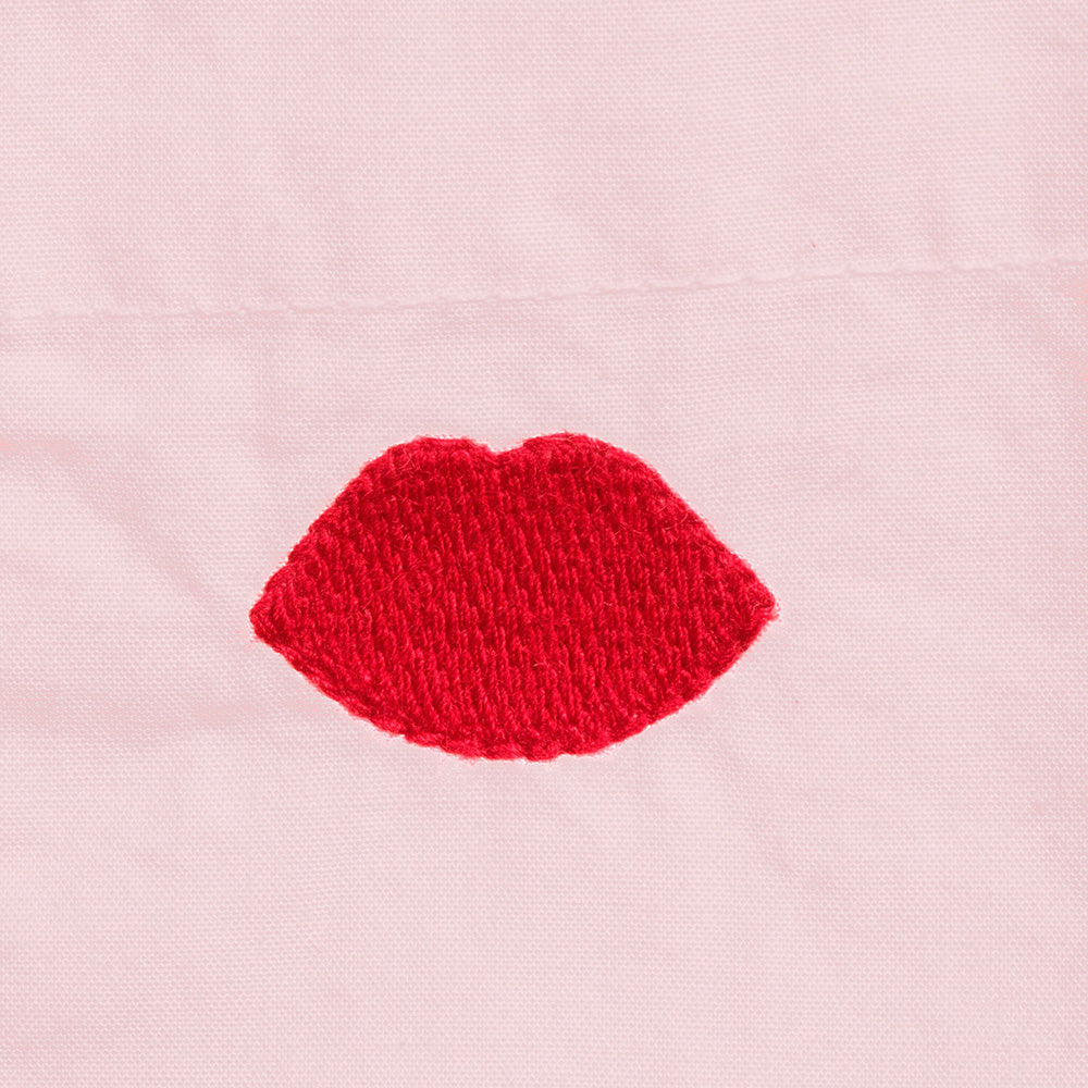 Close up image the red embroidered lip on a pink shirt