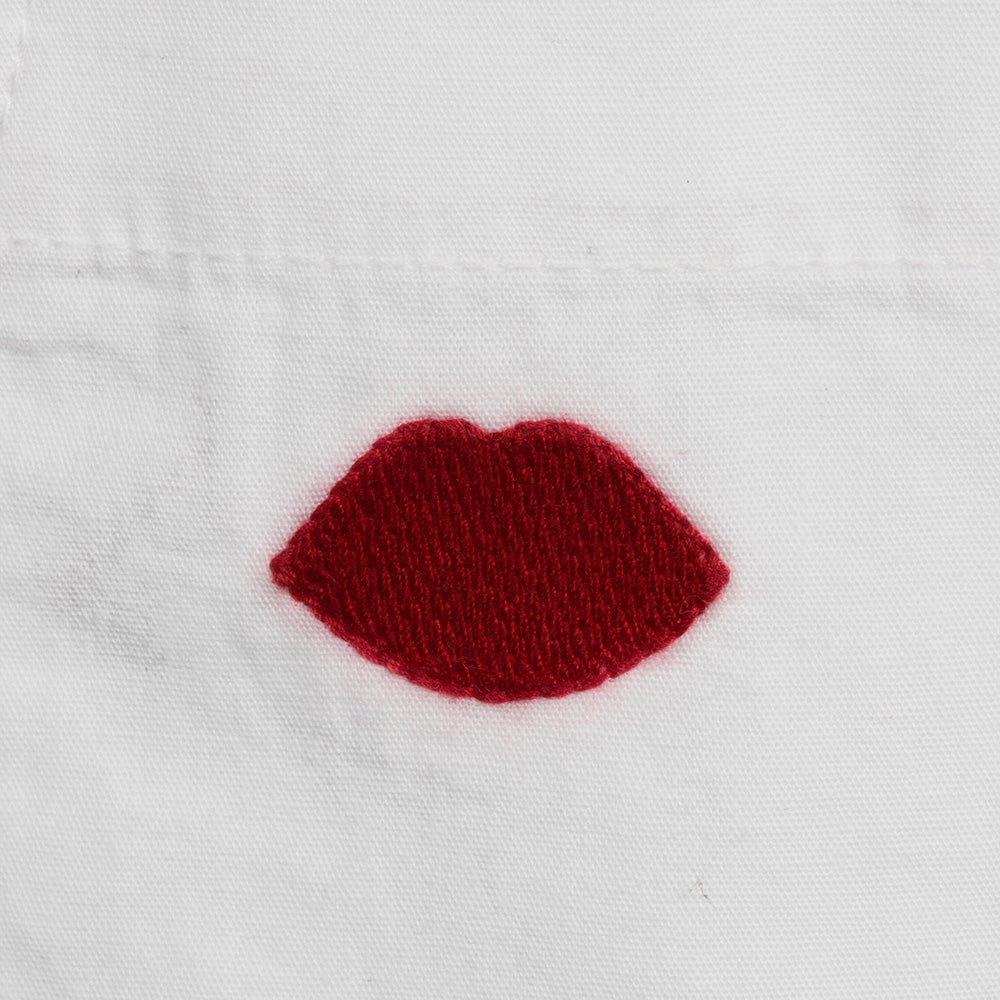Red embroidered lips on a white cotton shirt background