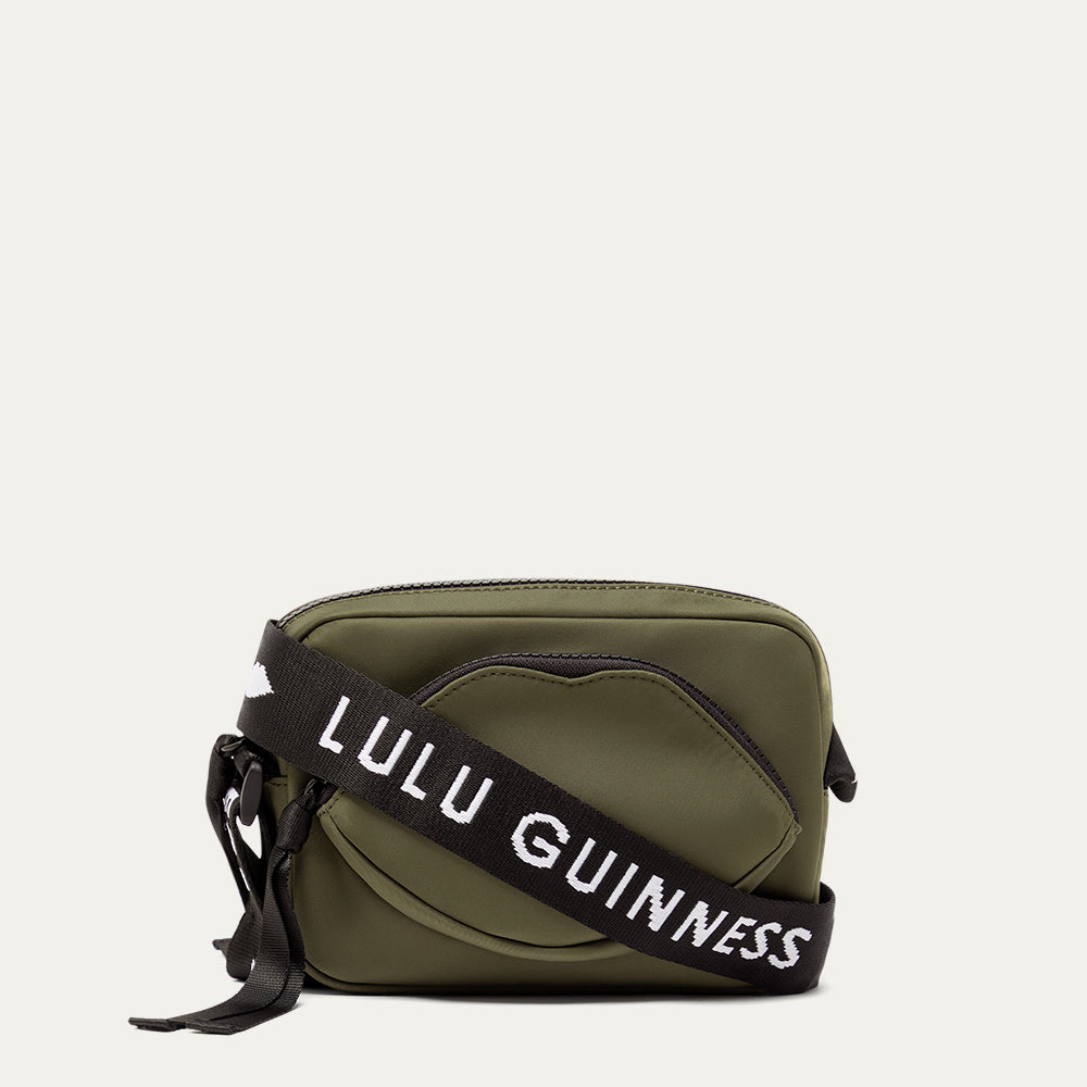 Green crossbody bag with a black strap featuring 'Lulu Guinness' on a white background