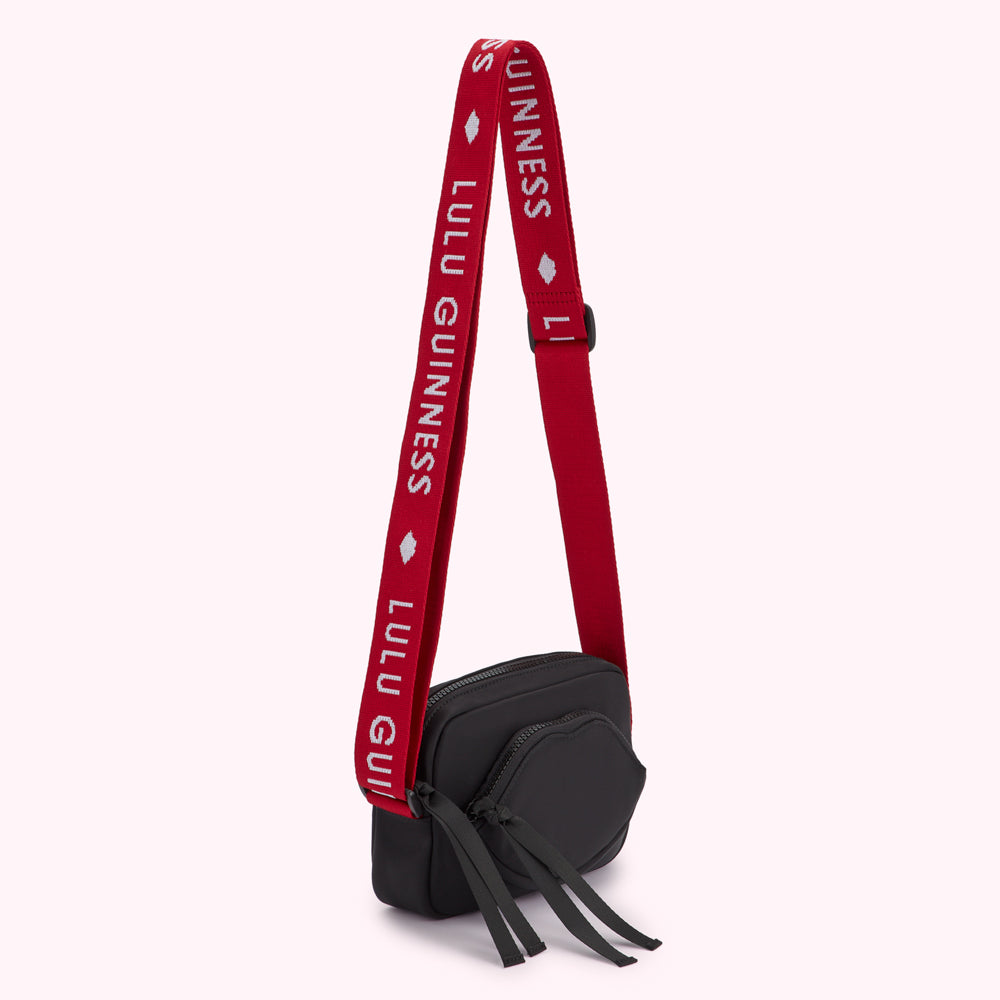 Black Lulu Guinness crossbody bag with red branded strap.