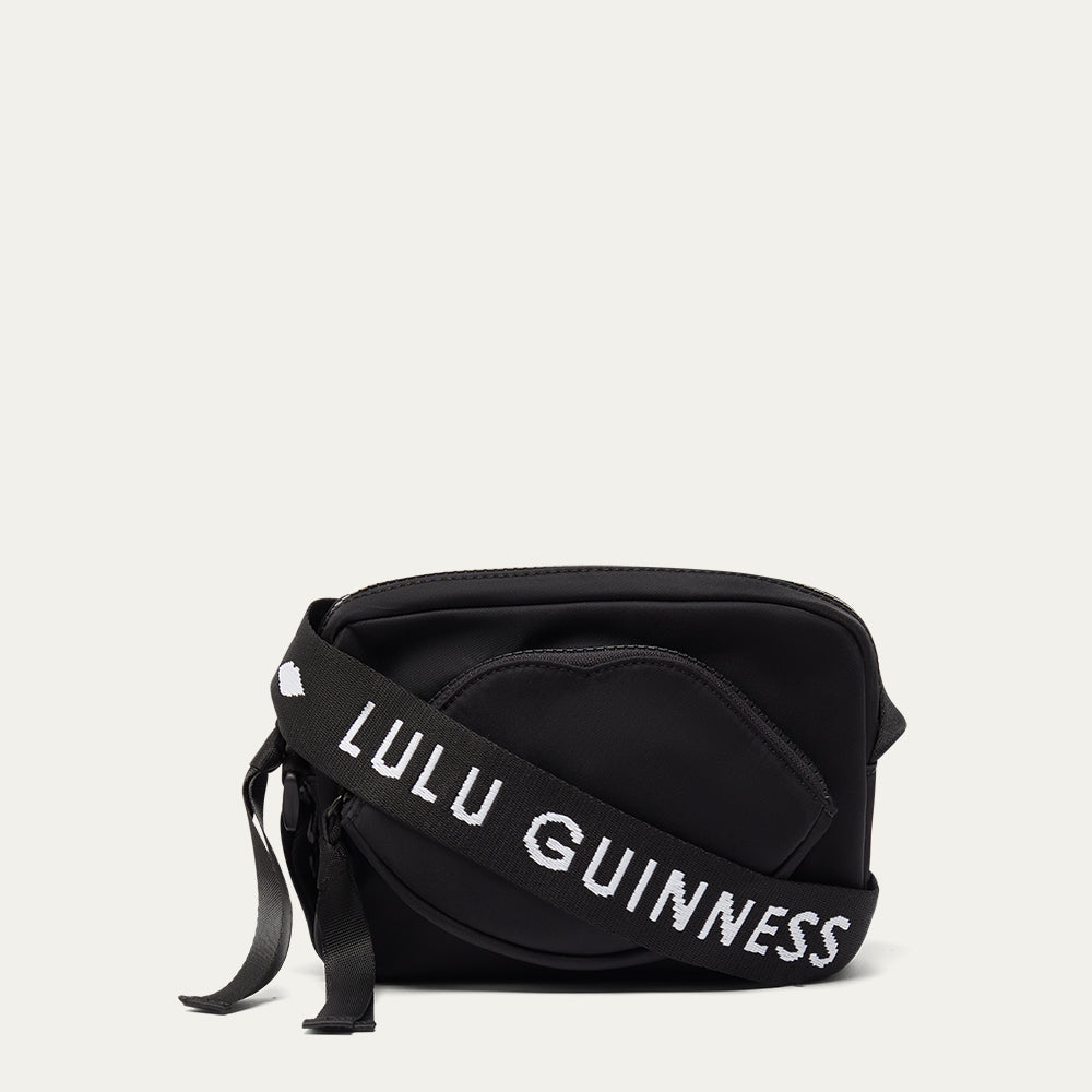 Black bag with 'Lulu Guinness' branded strap on a light gray background