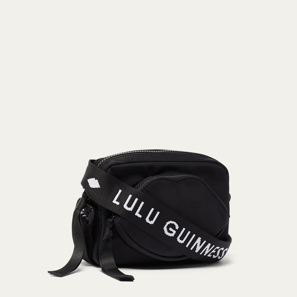 Black bag with 'Lulu Guinness' strap on a light gray background