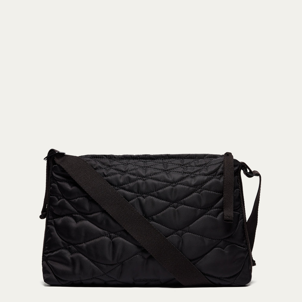 Black quilted shoulder bag on a light beige background