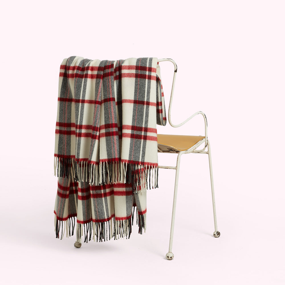 Cream, red, and grey plaid or tartan throw draped over a white metal chair.